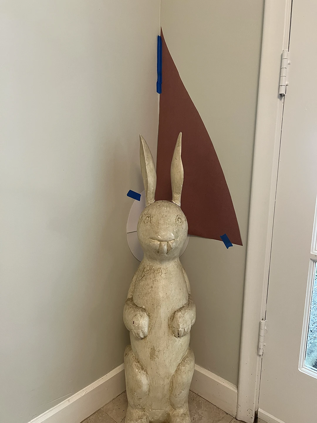 Rabbit shrine process photo showing taped paper cutout shapes on the wall around the rabbit.