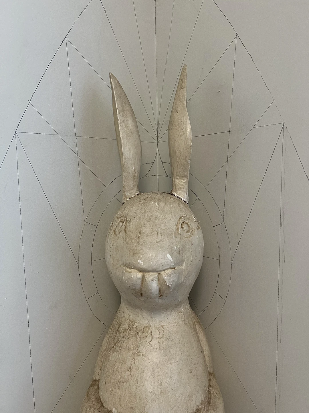 Close-up of the rabbit shrine before painting, showing the weathered white rabbit and pencil lines for the shrine geometry