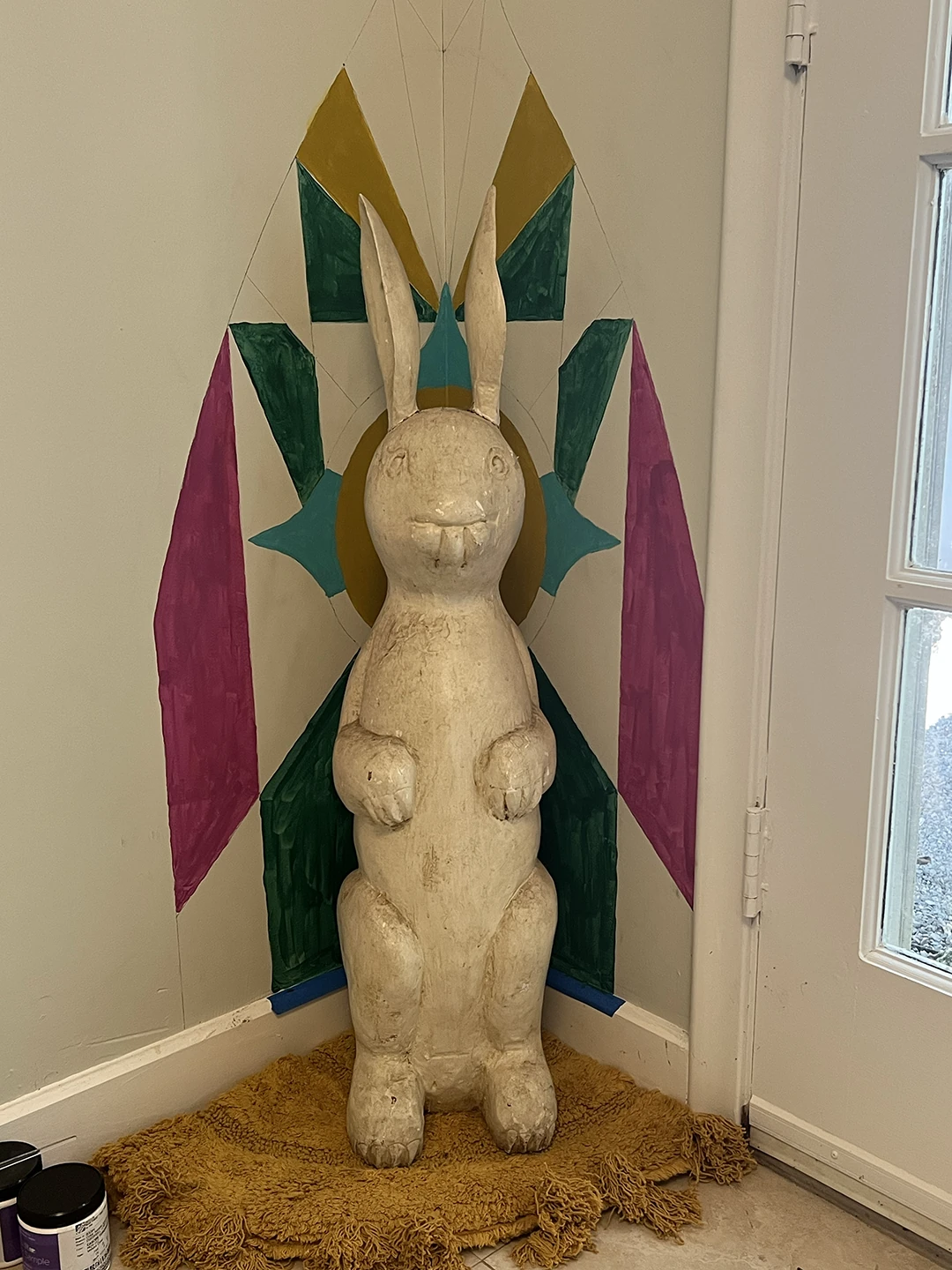 Rabbit shrine process photo showing the wall partway through painting with green, aqua, pink, and gold sections filled in.